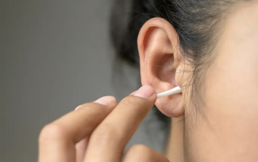 Woman cleaning her ear with a cotton swab